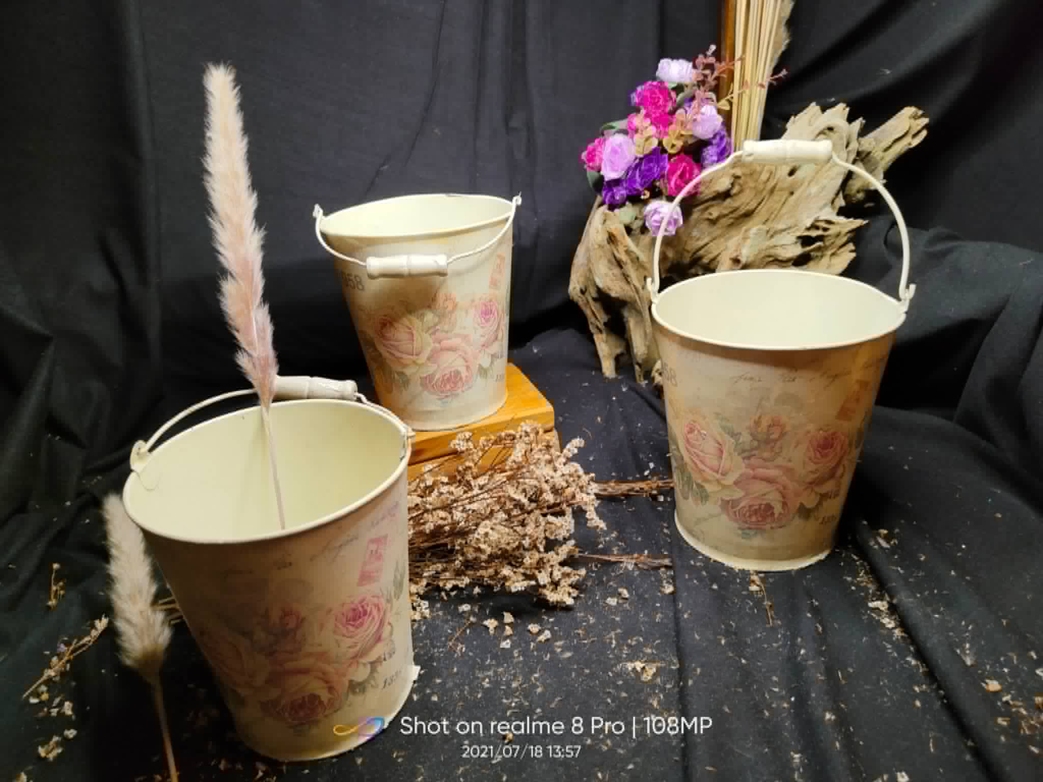 Three floral-patterned metal pails in assorted sizes