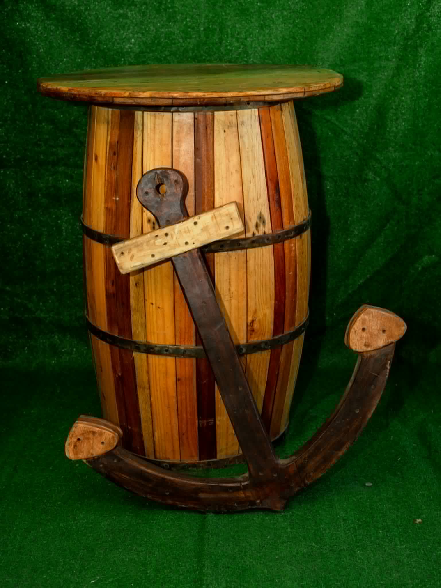 Decorative rustic anchor leaning against a wooden barrel table