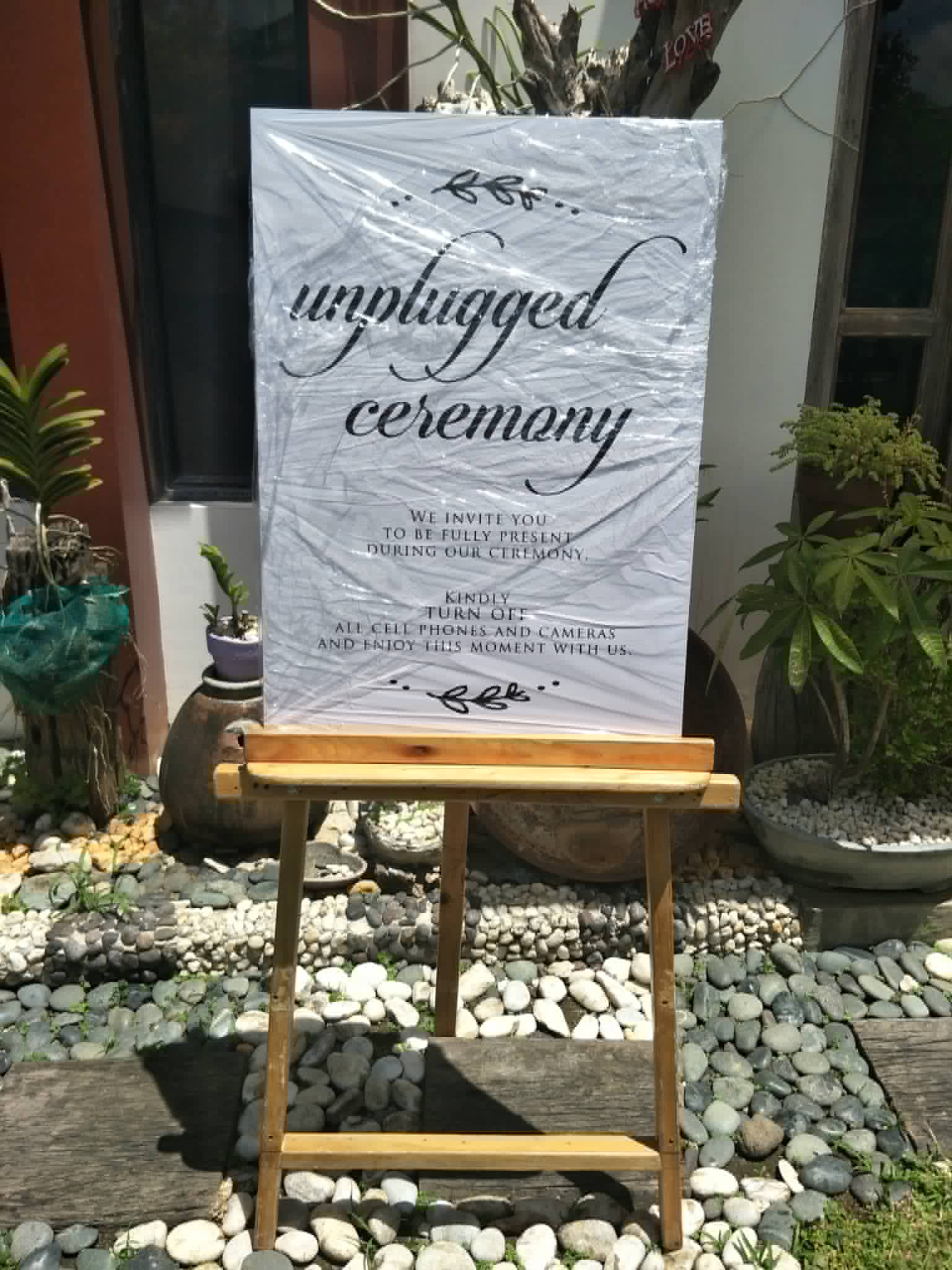 White unplugged ceremony sign displayed on a wooden easel