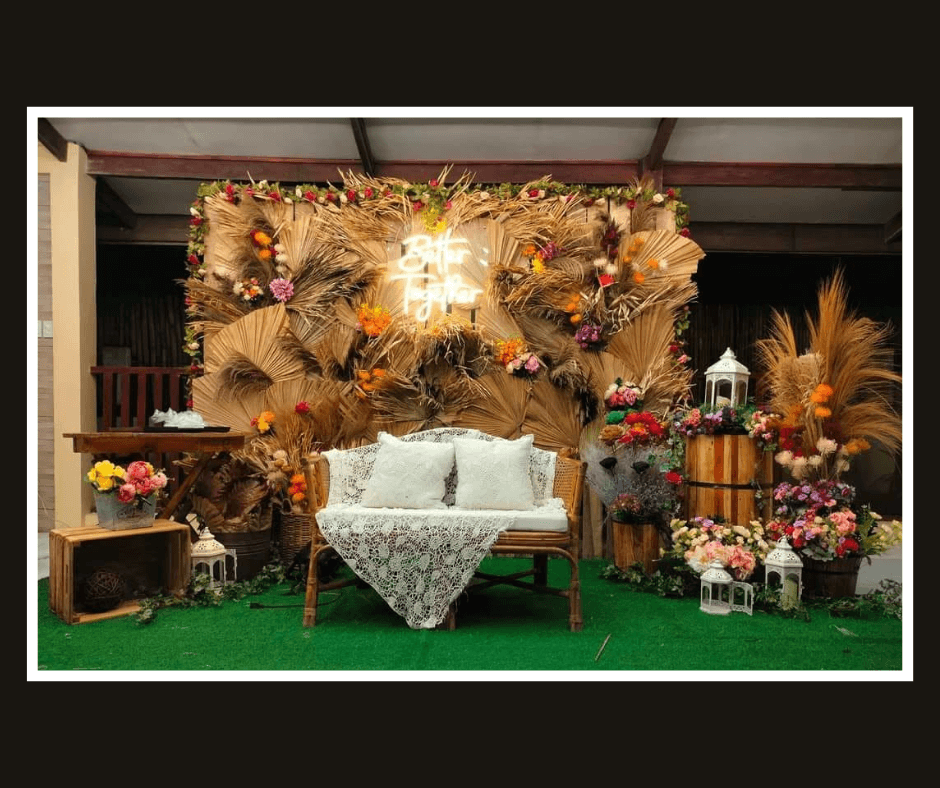 Dark rustic lounge wall with autumn foliage, flowers, lanterns, and a white loveseat