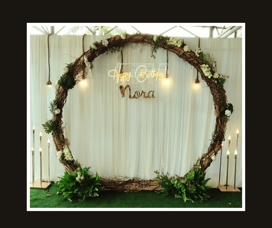 Large circular arch wrapped with greenery and flowers against white drapery
