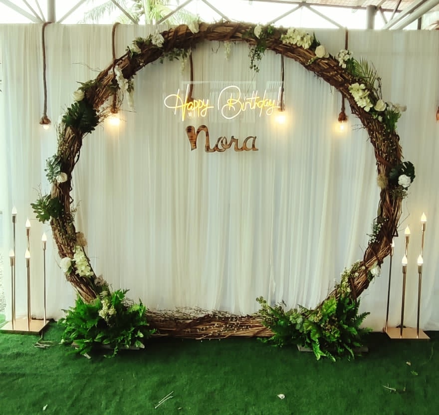 Large circular greenery hoop against white drapery with event lettering