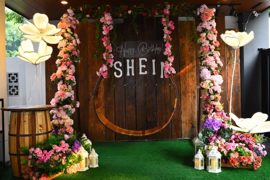 Rustic wood backdrop with a large horseshoe, pink flowers, and illuminated floral accents