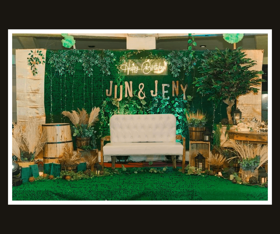 Dense green hedge backdrop with pampas grass, warm lettering, and a white loveseat