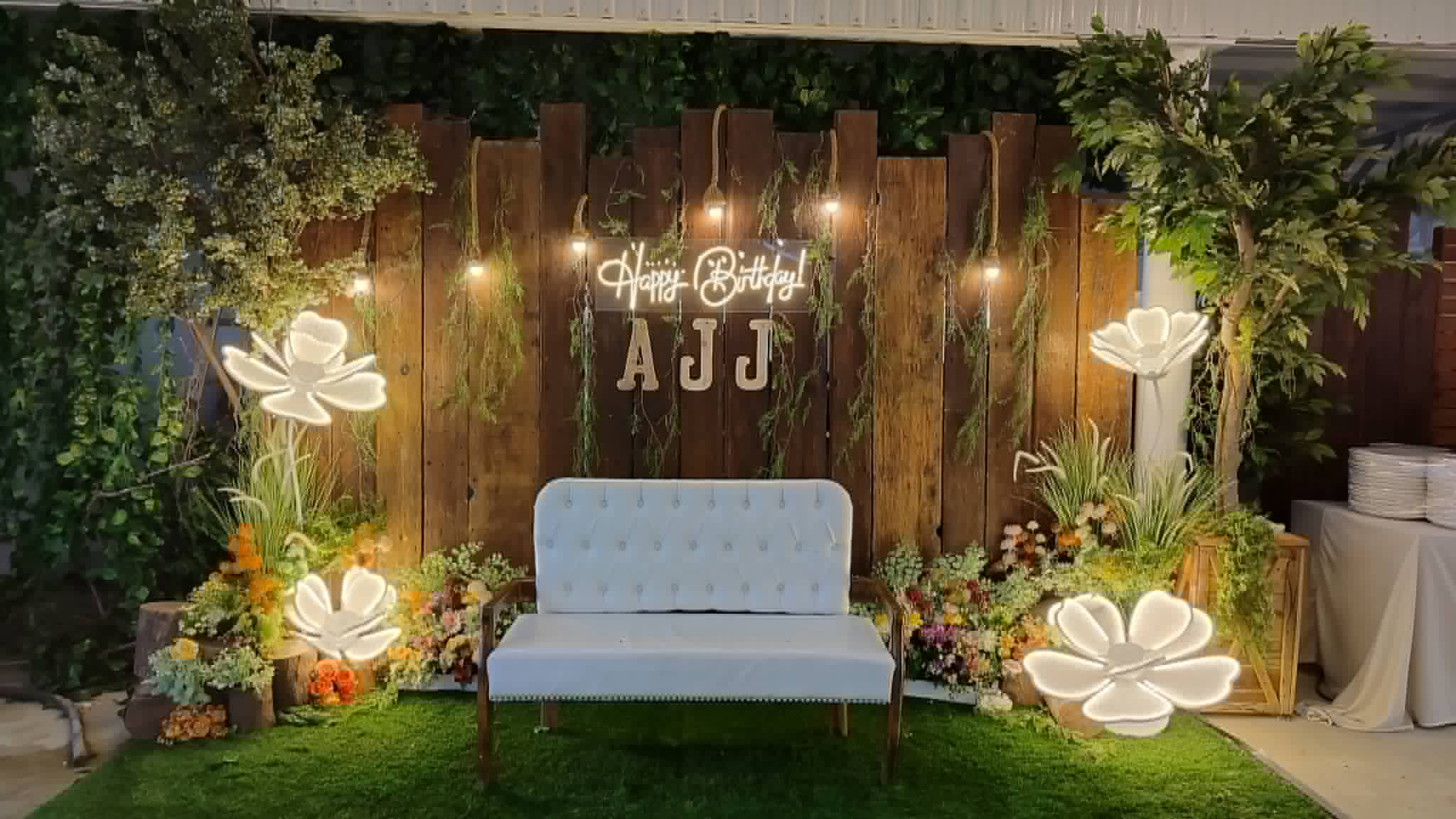 Illuminated wooden garden wall with floral lights and a white bench