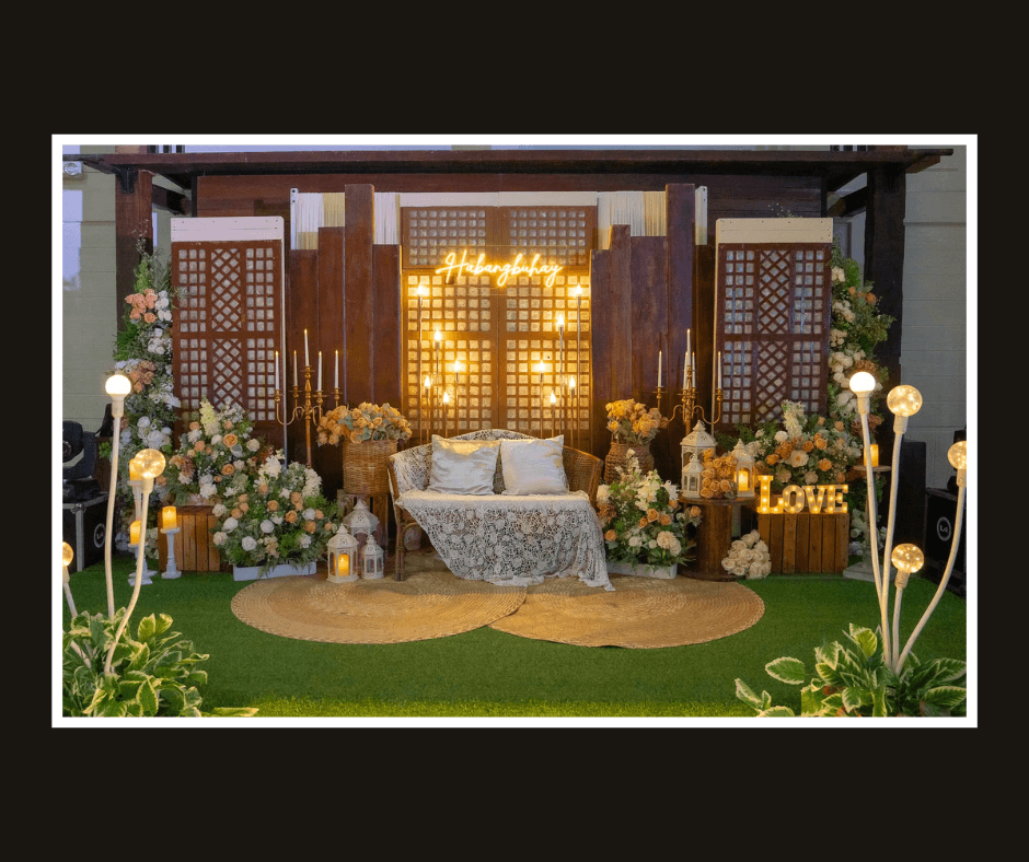 Wide rustic lattice and wood stage wall with warm lights, flowers, and a white loveseat