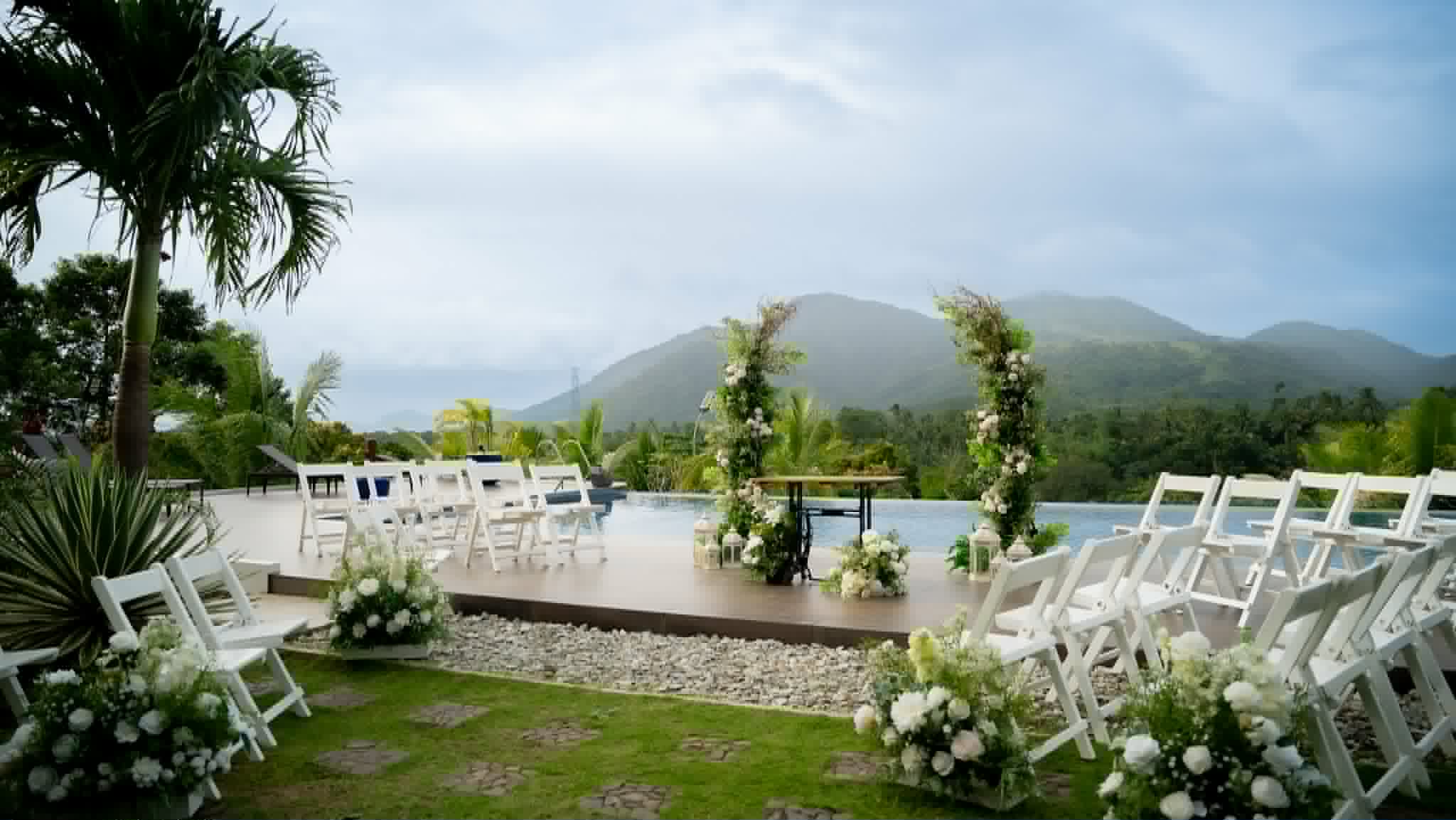 Outdoor white-chair ceremony layout overlooking a pool and mountain landscape