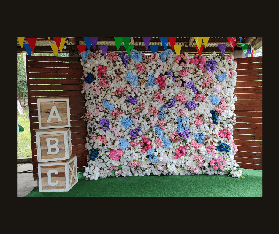 Pastel blue, pink, lavender, and white flower wall styled with letter blocks and party bunting