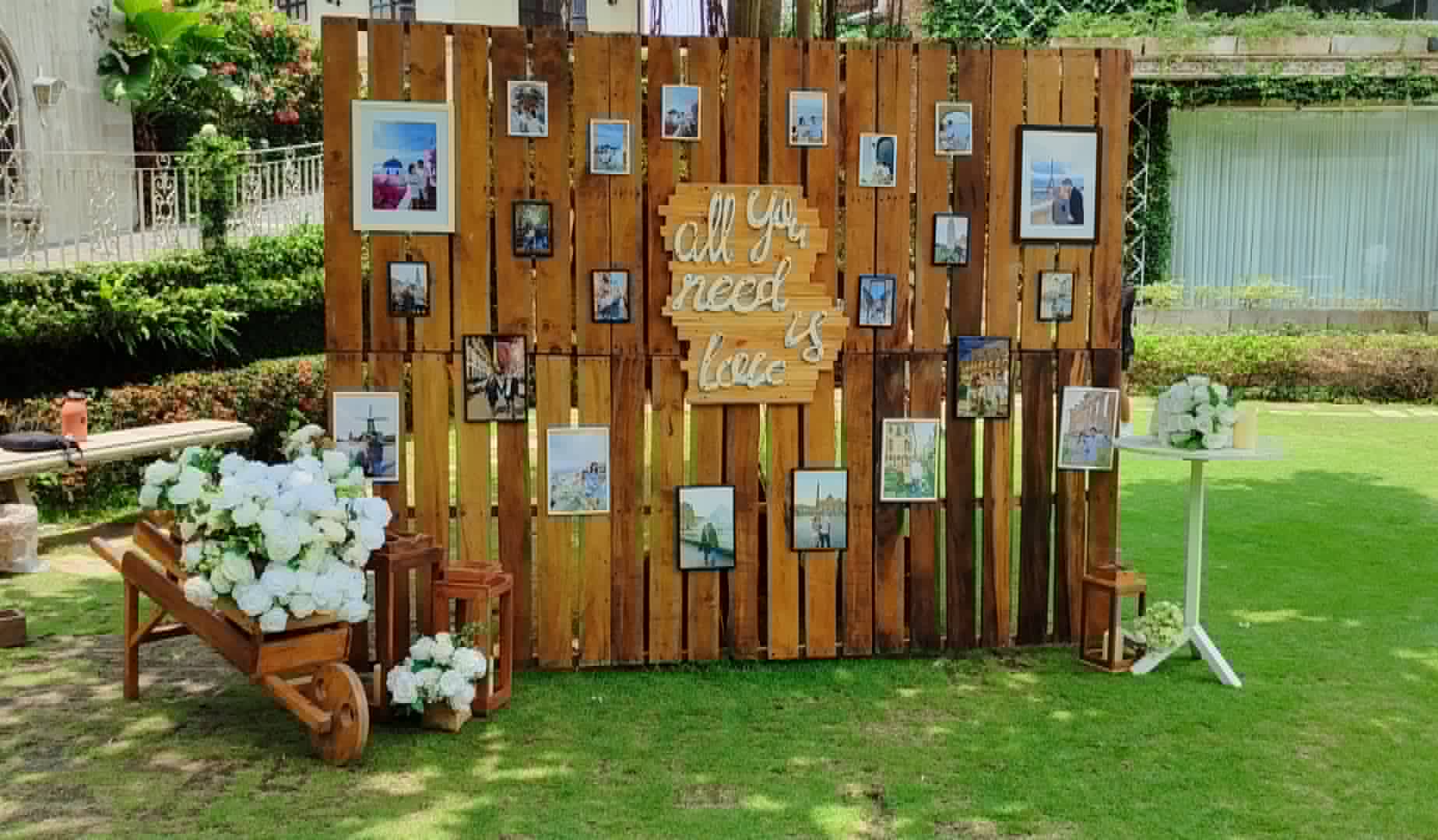 Rustic wooden wall decorated with framed photographs, flowers, and lettering