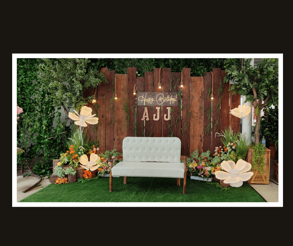 Rustic vertical plank wall with hanging warm lights, tropical flowers, and a white bench