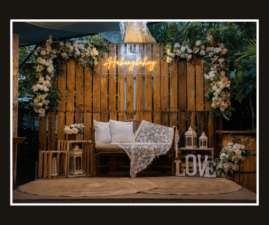 Rustic vertical plank wall with flowers, warm script lighting, and a white loveseat