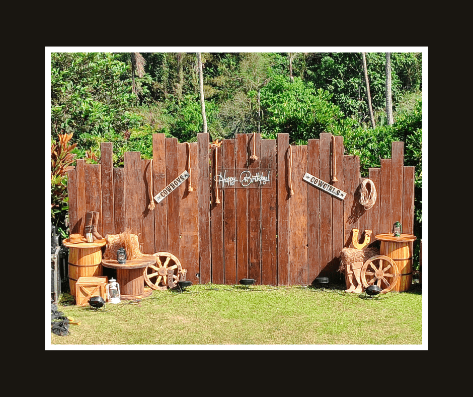 Curved rustic plank wall decorated with rope, horseshoes, wagon wheels, barrels, and lanterns