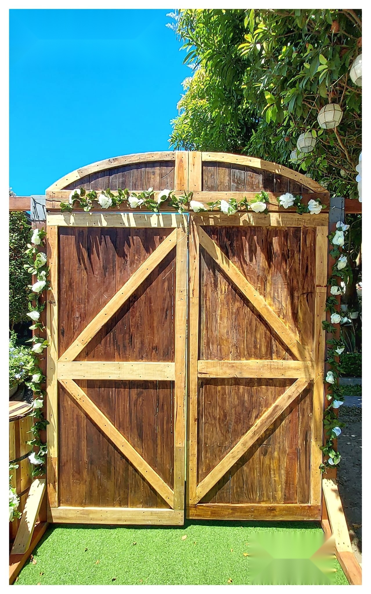 Rustic double wooden gate framed with greenery and white flowers