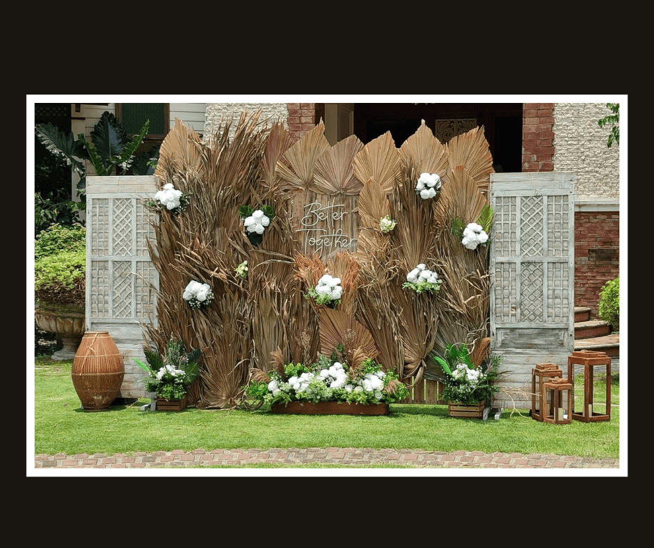 Layered dried tropical palm leaf wall with white flowers and lattice side panels