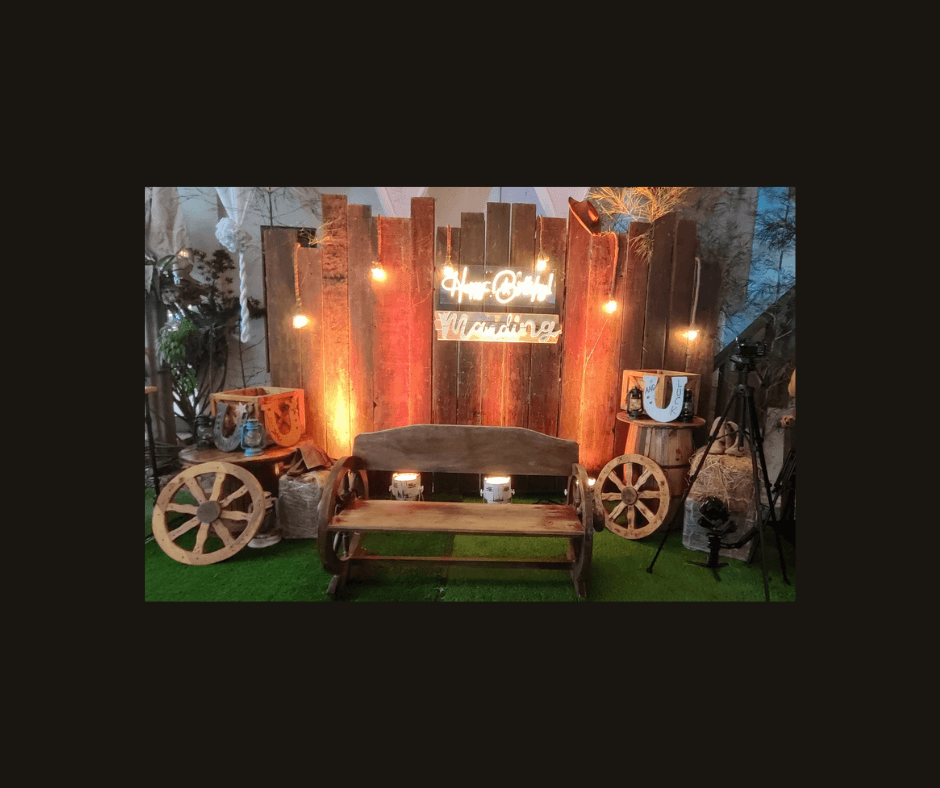 Dark western lounge backdrop with wagon wheels, rope, warm lights, and a brown loveseat