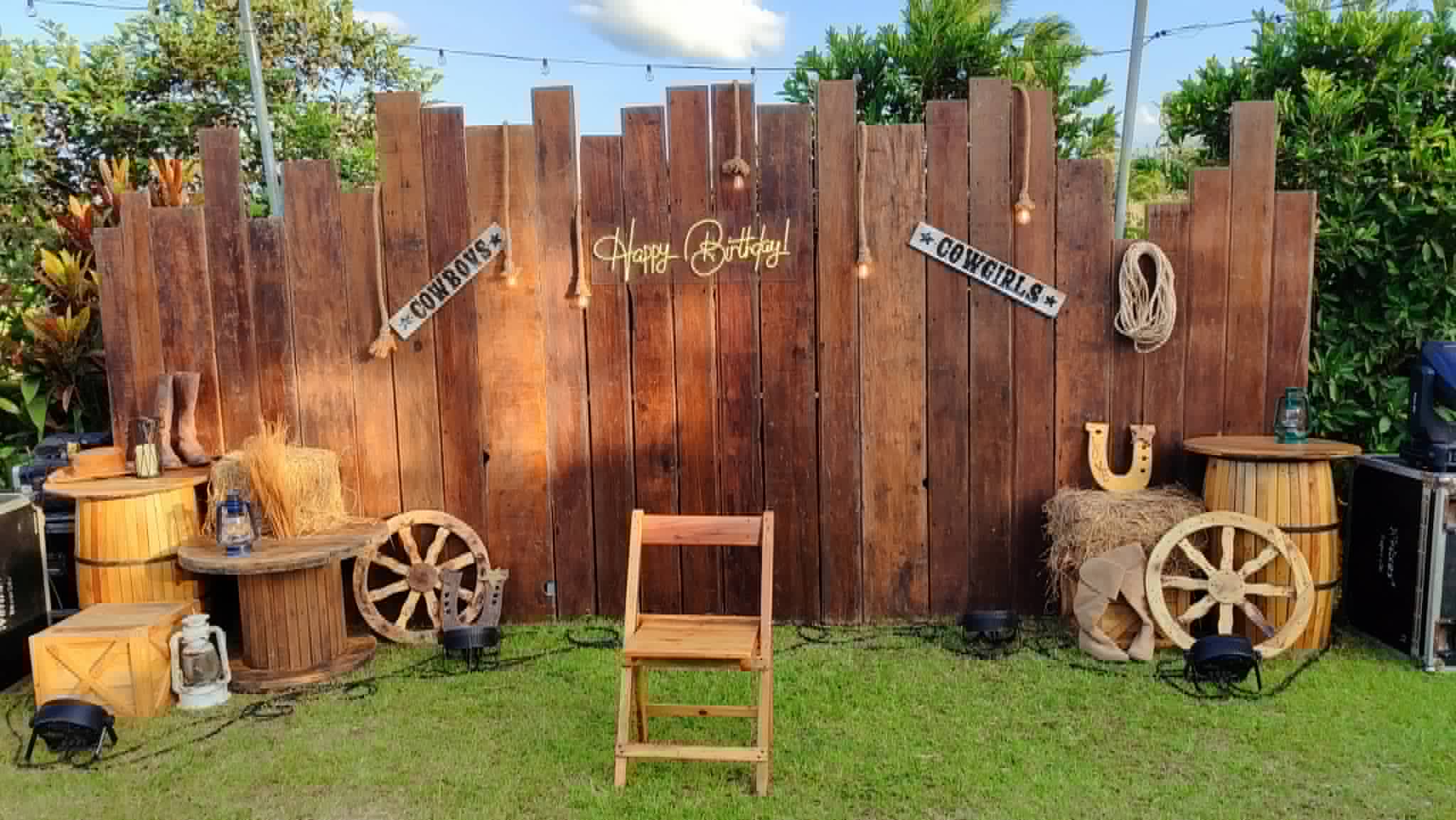 Western-themed rustic wood panel backdrop with barrels, crates, signs, and wagon wheels