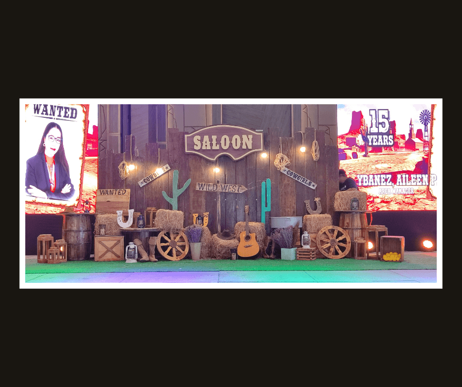 Western saloon stage with timber storefronts, wagon wheels, posters, and guitars