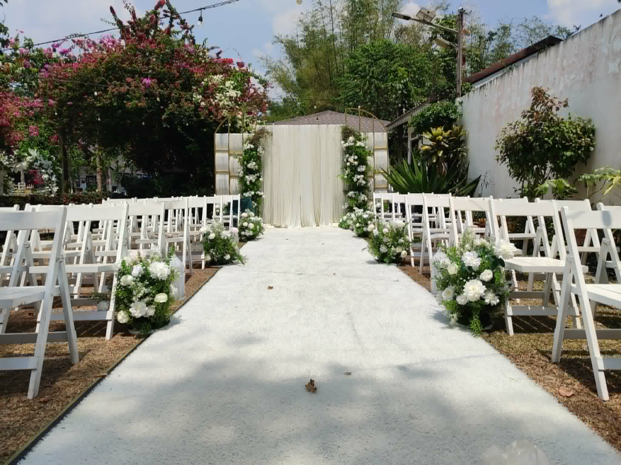 White garden ceremony aisle leading to a softly draped backdrop