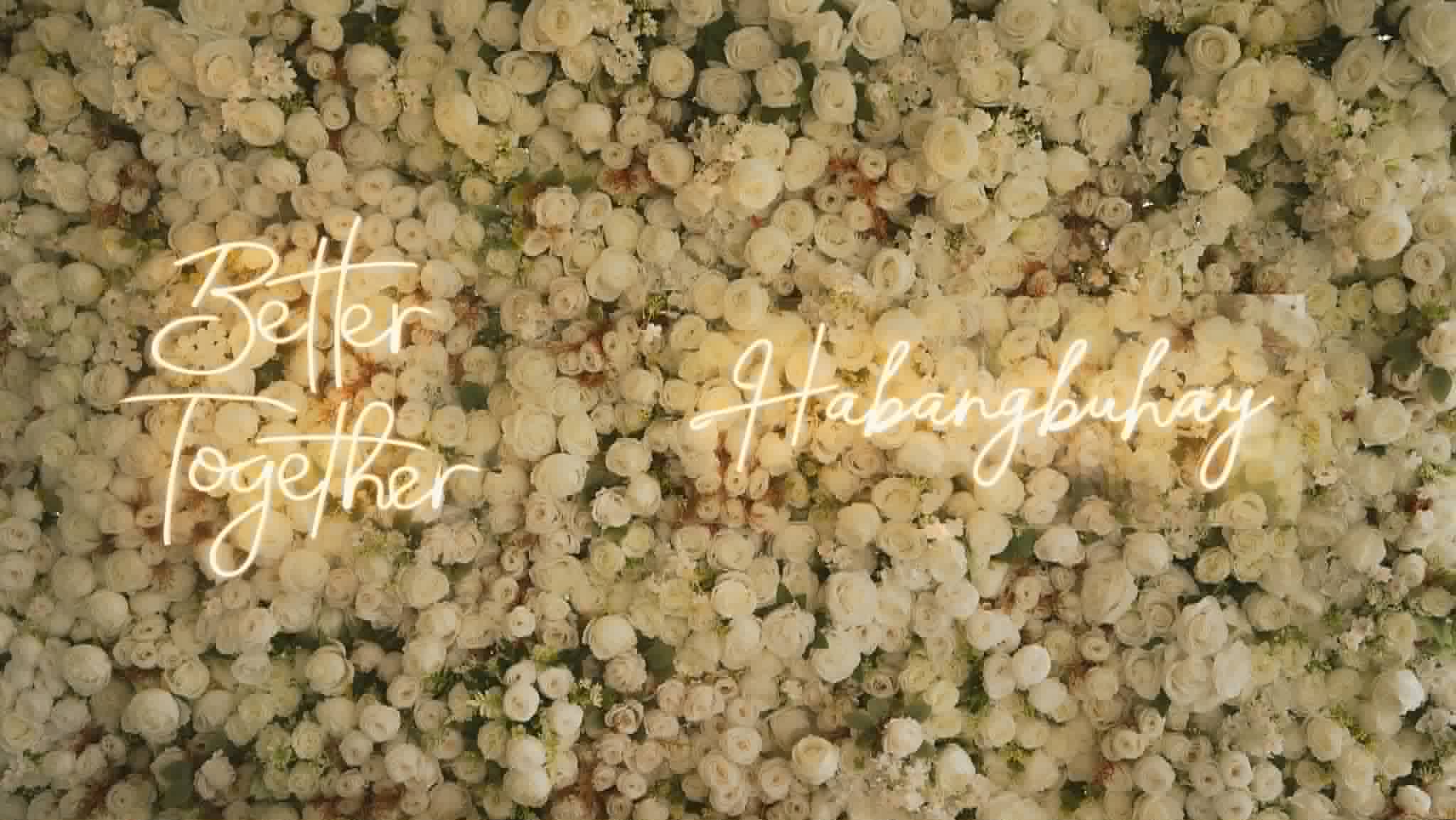 Dense white flower wall with warm neon wedding lettering