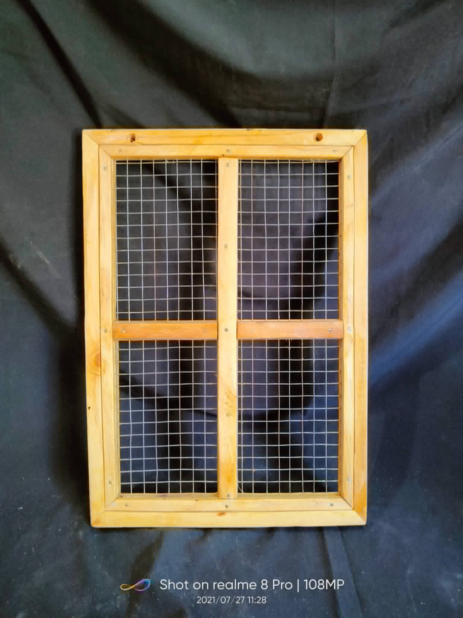 Rectangular natural wood window frame with black wire mesh