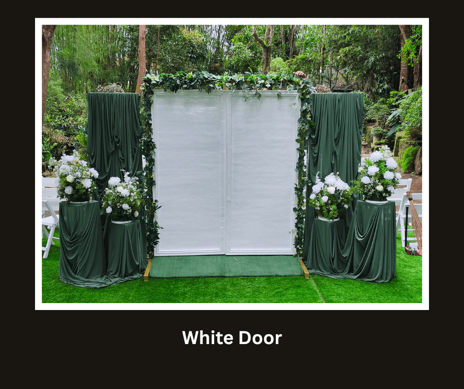 Freestanding white double door framed by green draping and flowers