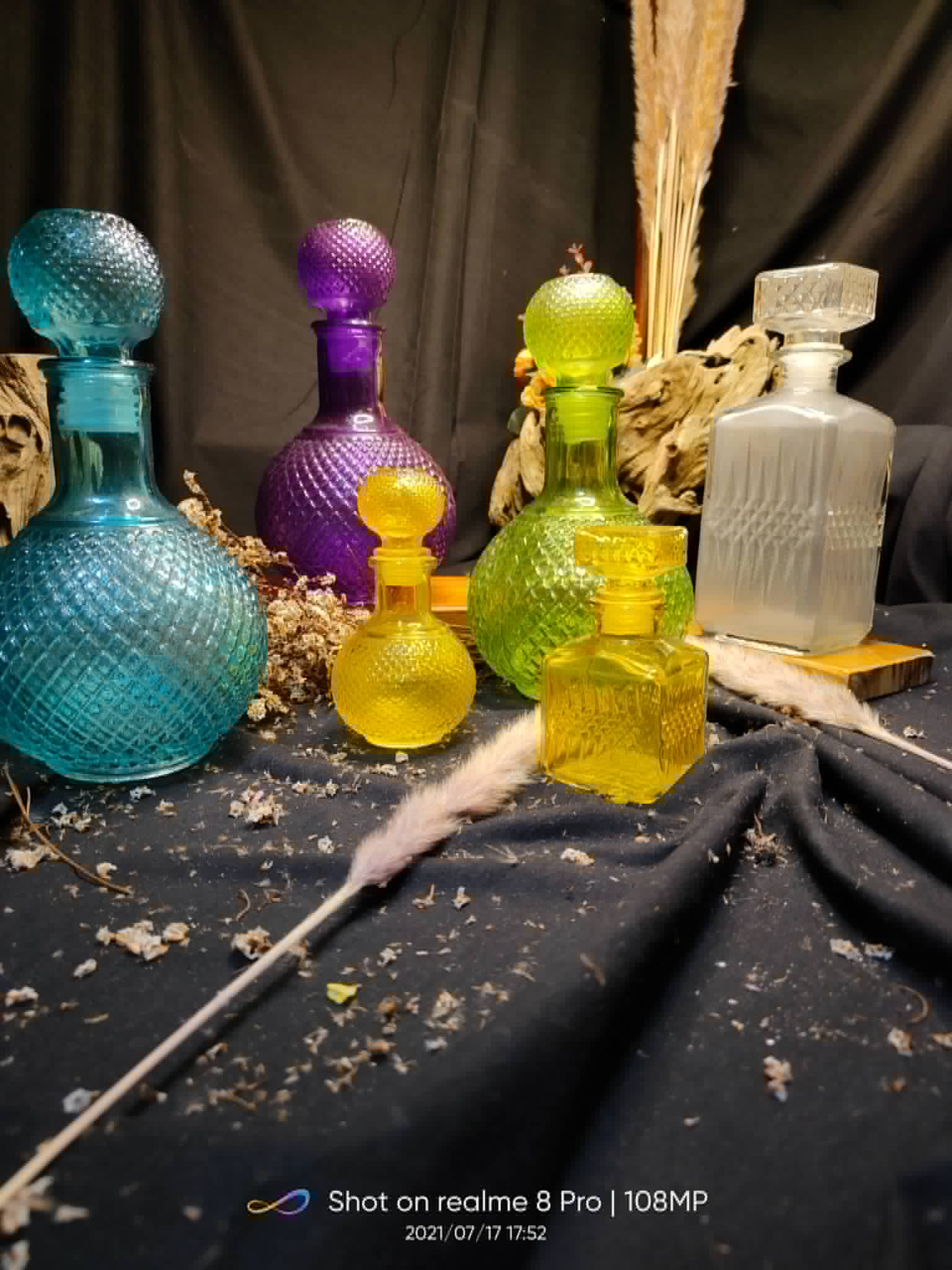 Assorted decorative glass bottles in blue, purple, green, yellow, and clear finishes