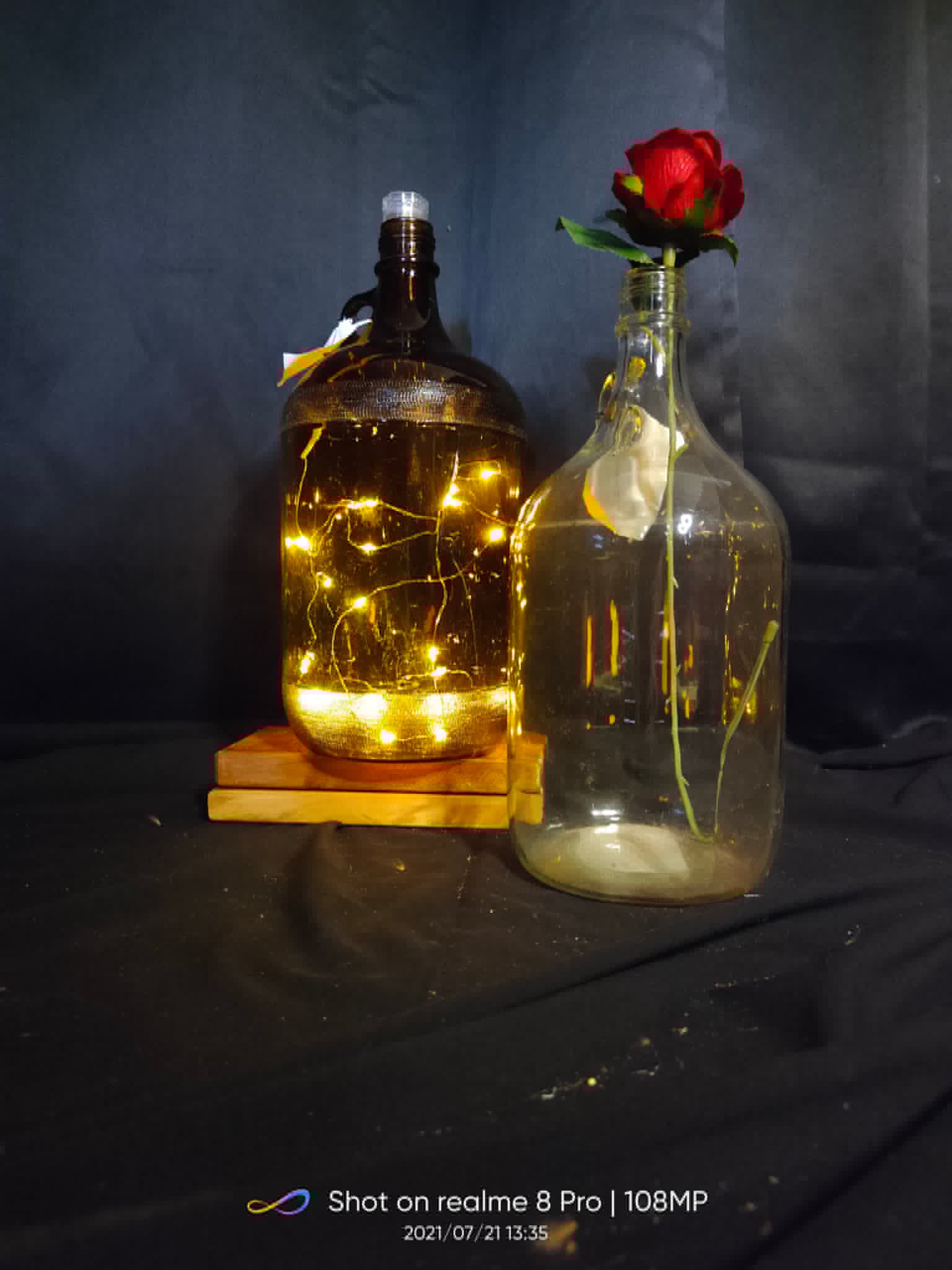 Decorative glass bottles with warm fairy lights and a single rose