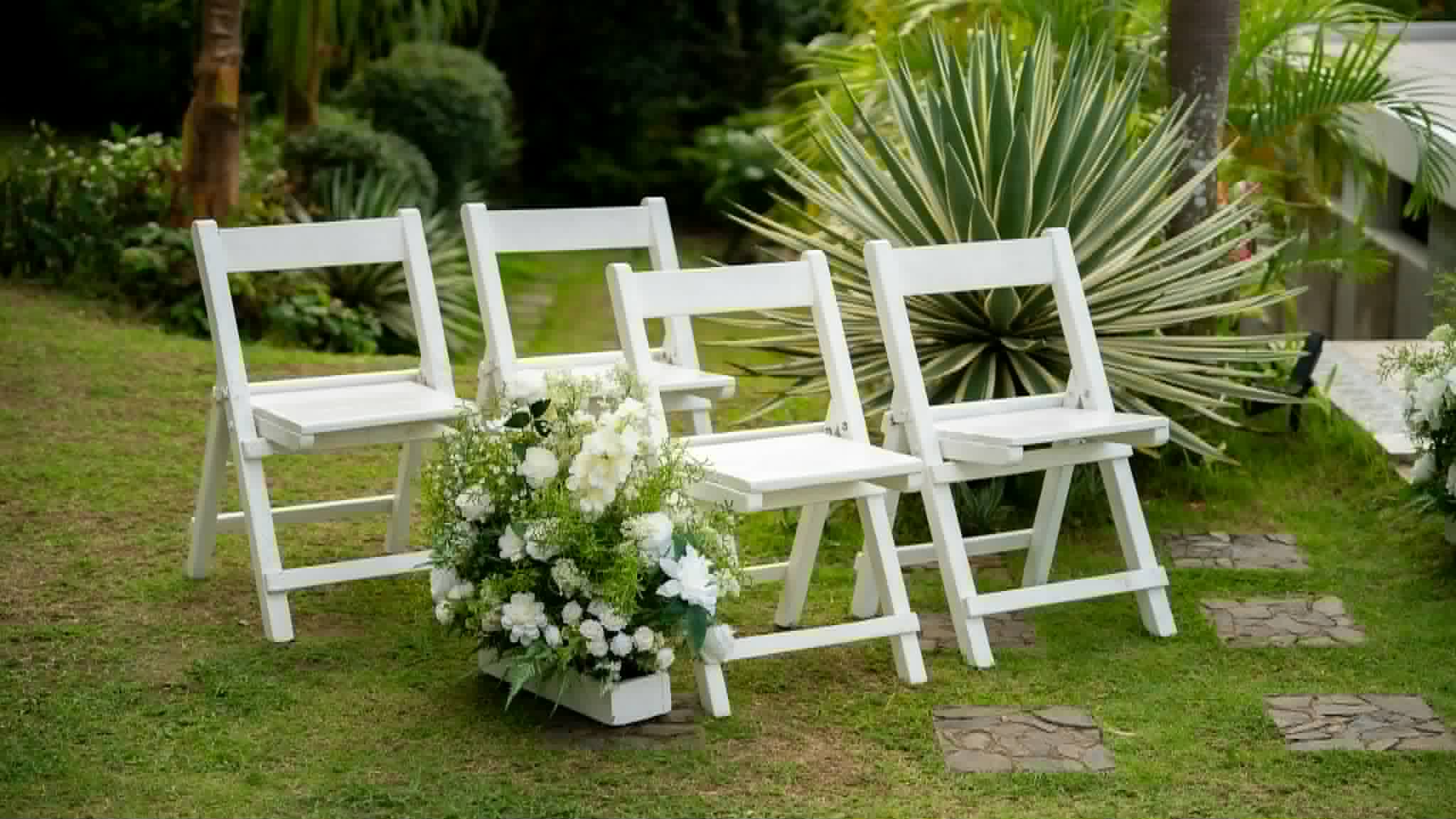 Three white wooden ceremony chairs arranged with white floral accents