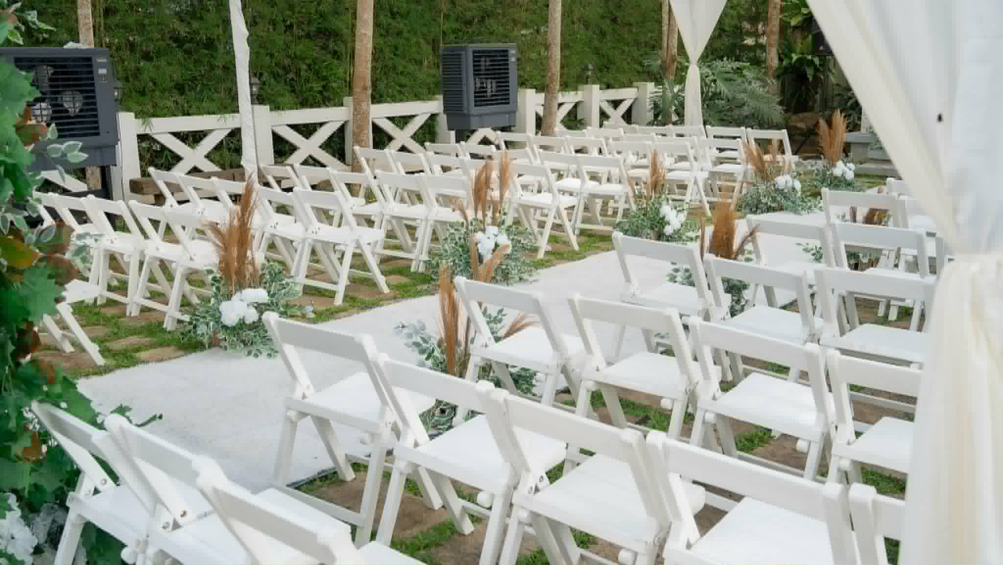 Close view of white wooden wedding chairs with white and dried floral aisle details