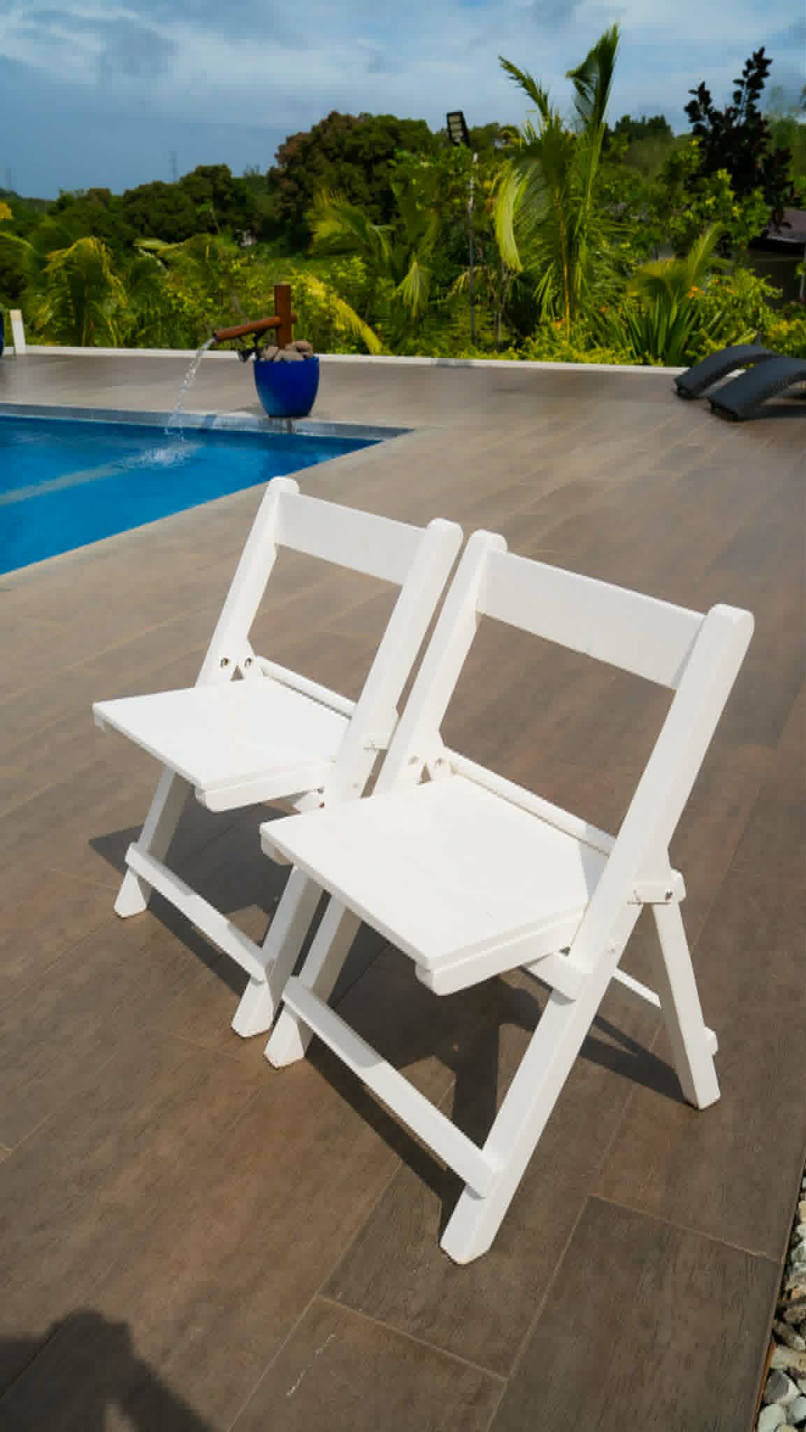 White folding chairs staged by a pool