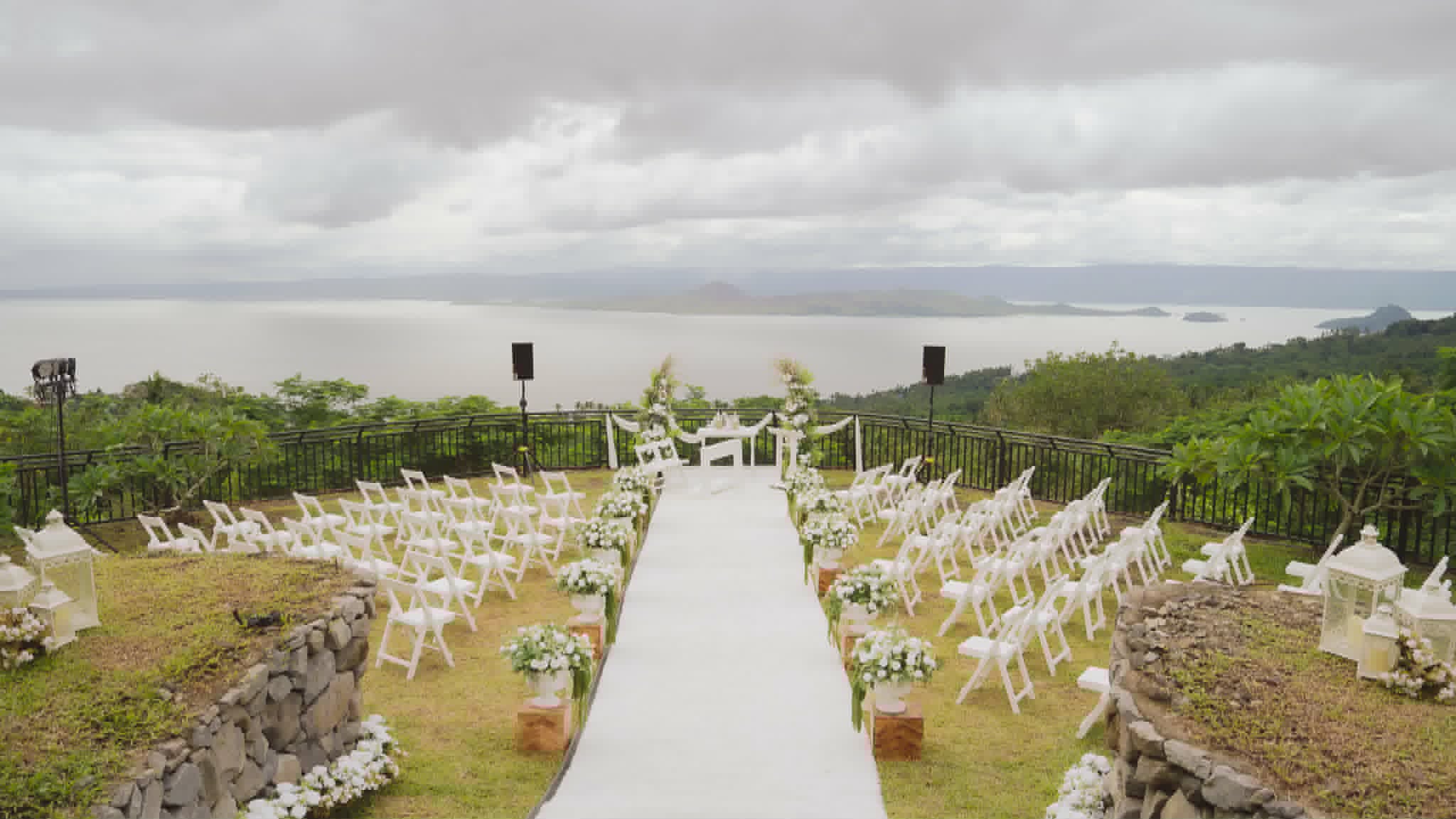 Large outdoor wedding aisle with white chairs overlooking the lake