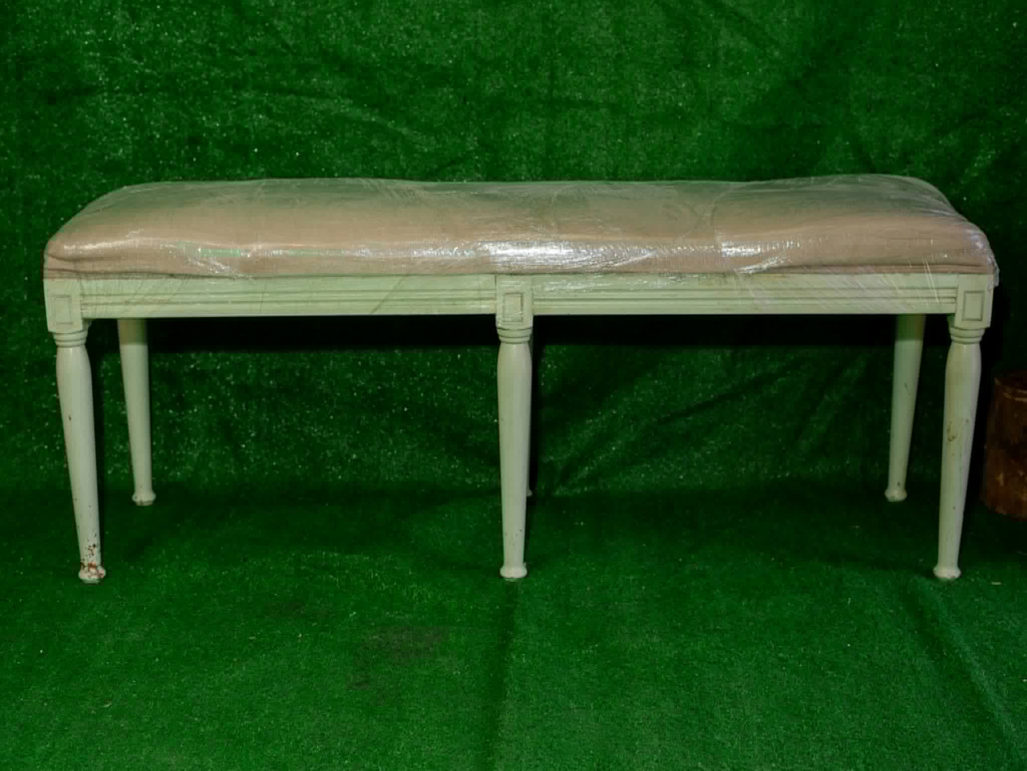 Long white upholstered bench with slender decorative legs