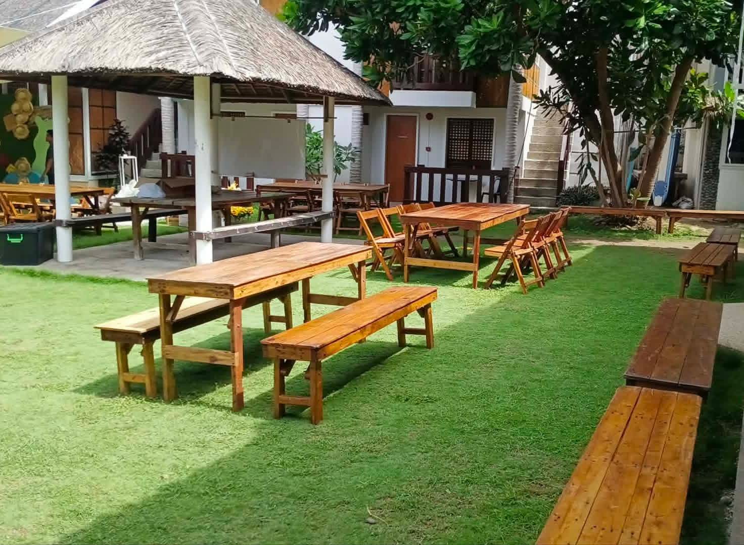 Long rustic wooden benches paired with wooden banquet tables in a garden
