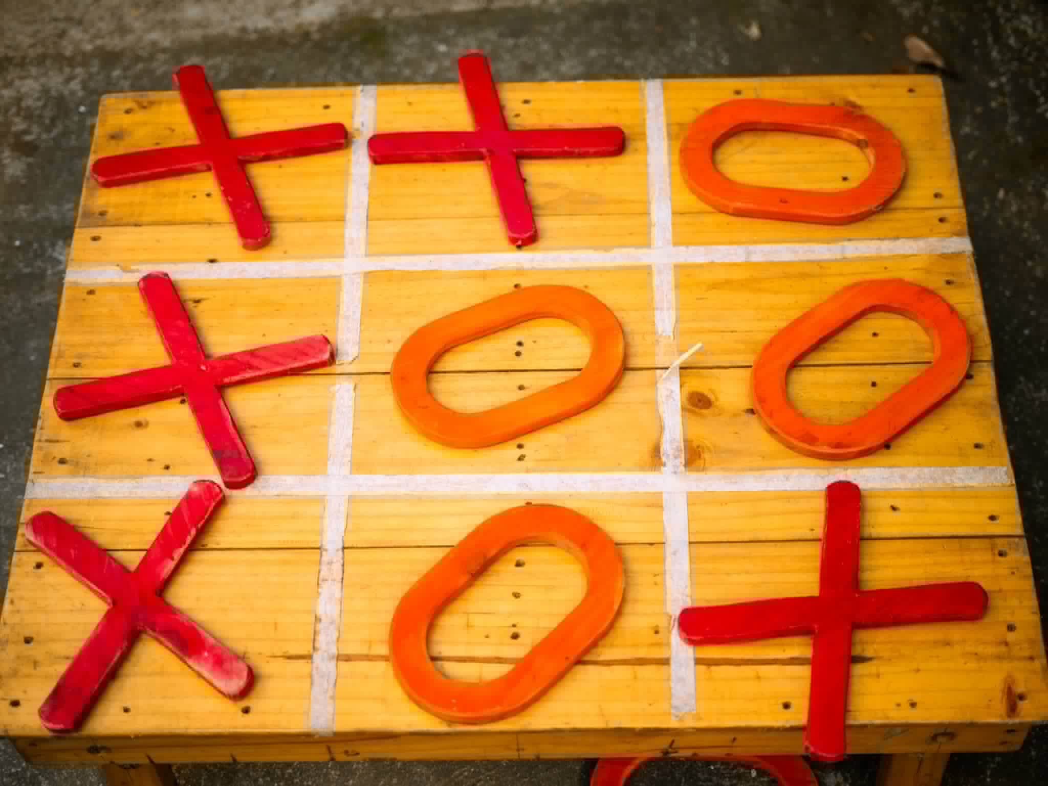 Oversized wooden tic-tac-toe game with red X and O pieces