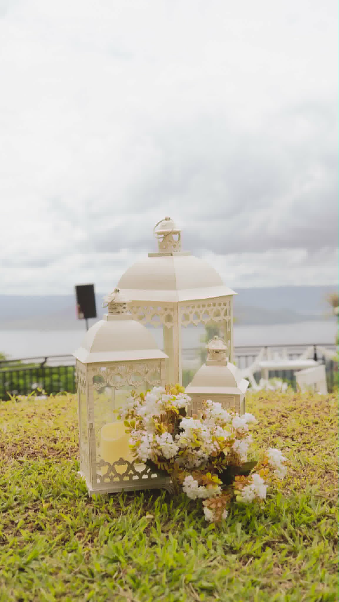Large white decorative lantern beside flowers overlooking the sea