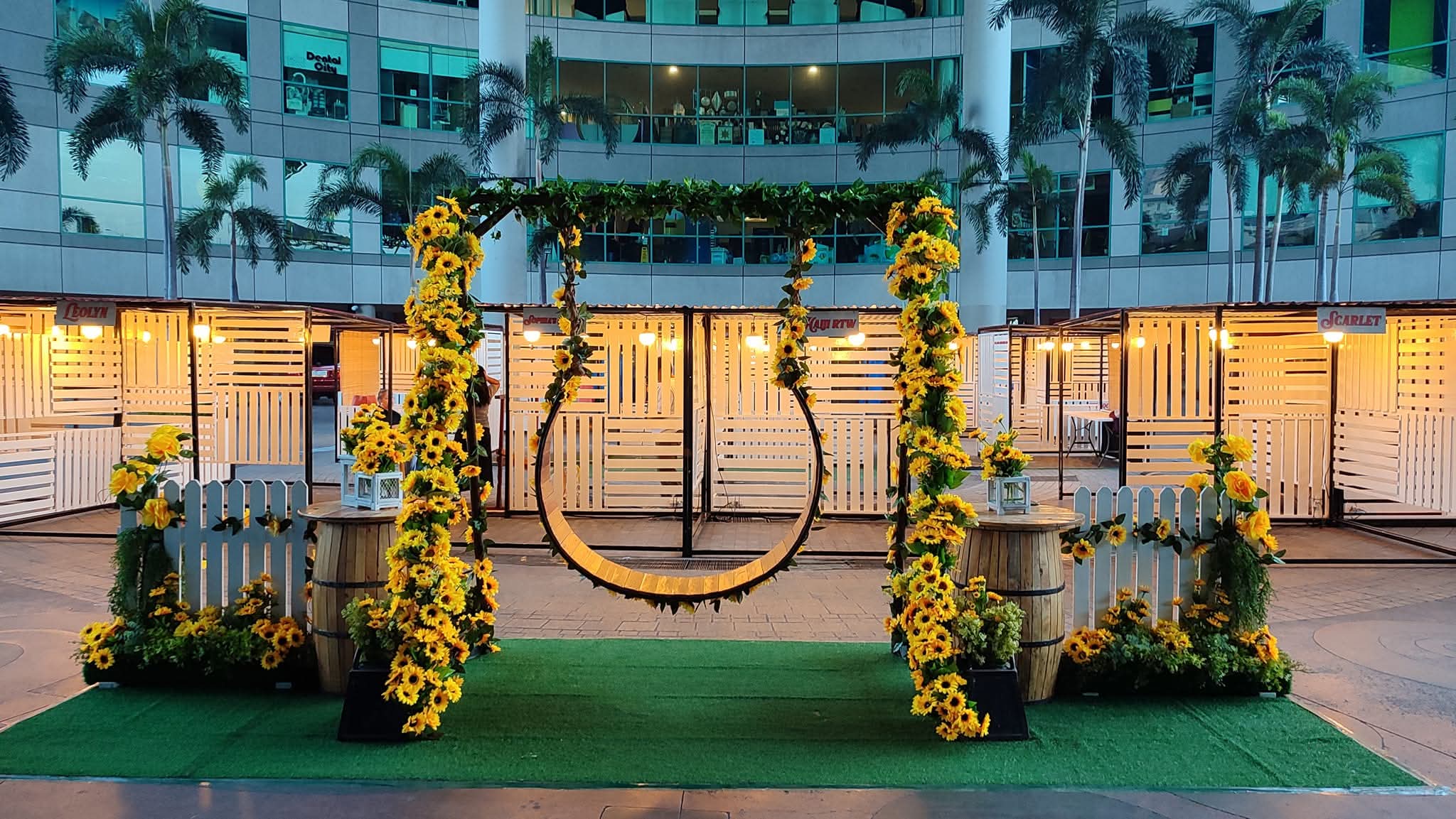 Sunflower-covered circular swing and barrel styling at a venue courtyard