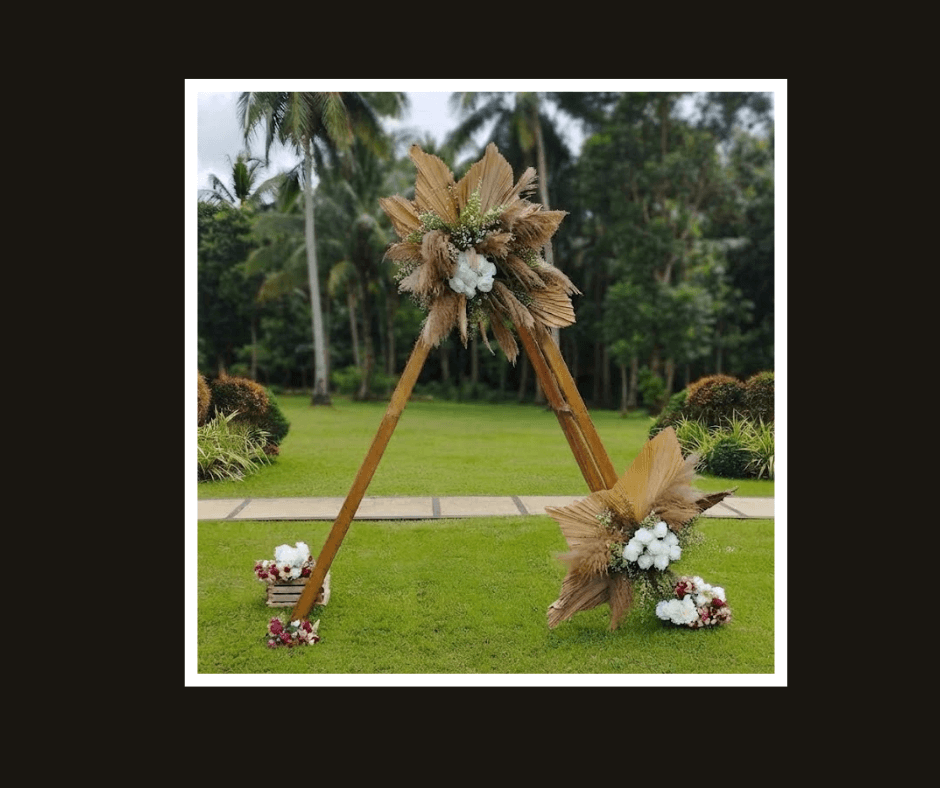 Freestanding triangular timber ceremony arch decorated with pampas grass and white flowers